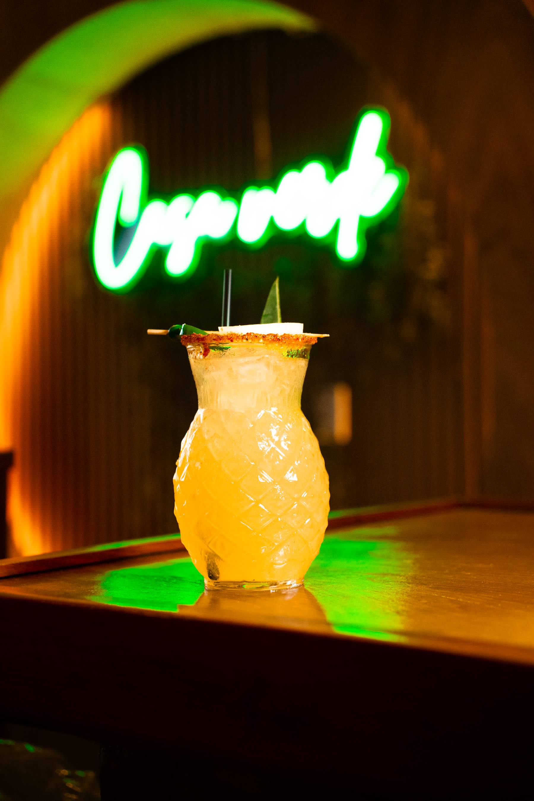 Tiki mug cocktail under Casa Verde neon sign